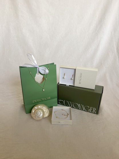 Jewelry set with necklaces and earrings in branded boxes on a white background