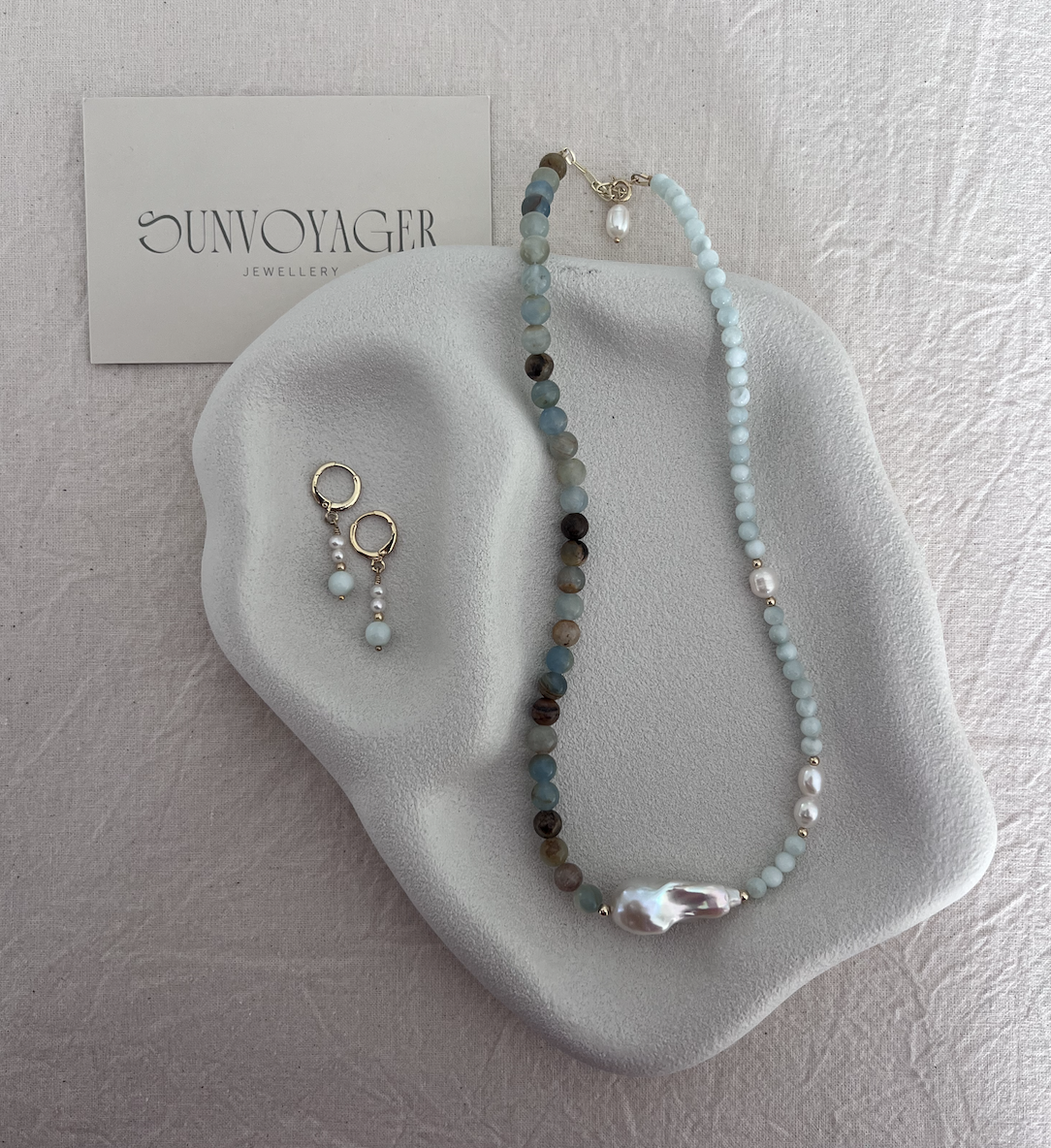 Asymmetric blue calcite and green angelite gemstone necklace featuring freshwater pearls, a central baroque pearl and 18k gold-filled details.